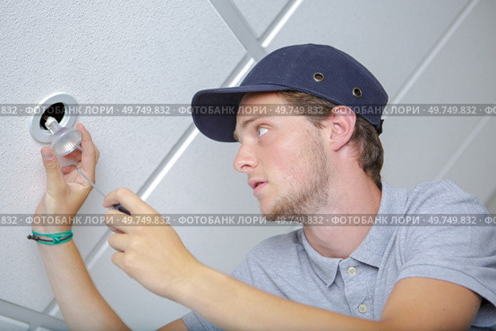 a male worker changing a lightbulb. Стоковое фото, агентство Ingram Publishing / Фотобанк Лори