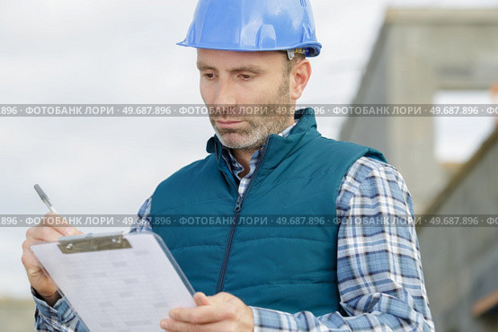 a man builder writing on a clipboard. Стоковое фото, агентство Ingram Publishing / Фотобанк Лори