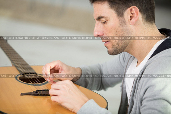 a man changes guitar strings. Стоковое фото, агентство Ingram Publishing / Фотобанк Лори