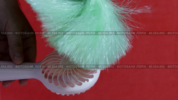 A man demonstrates the operating modes of a portable fan. Brings a brush to him, demonstrating the strength of the air flow. On a coral background. Close-up. Стоковое видео, видеограф Vadzim Yakubovich / Фотобанк Лори