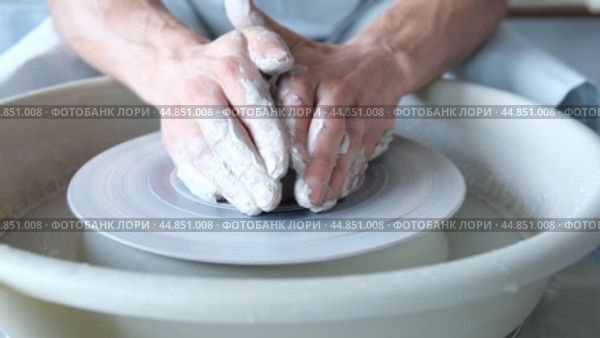 A man dries a white clay product with a hair dryer on a potter's wheel. Craft, creativity, the process of working on a potter's wheel. Стоковое видео, видеограф Терехова Марина / Фотобанк Лори