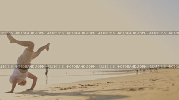 A man is showing martial arts - capoeira - on the beach at sunset. Стоковое видео, видеограф Константин Шишкин / Фотобанк Лори