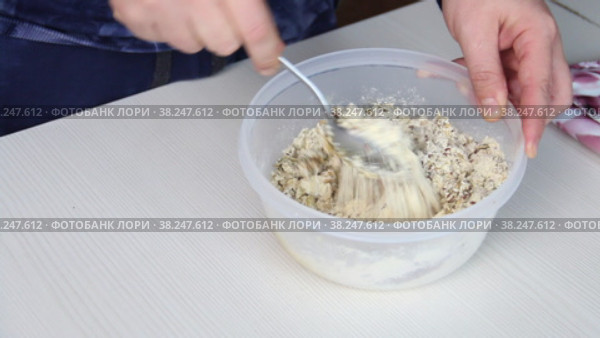 A man mixes ingredients for a multi-cereal loaf in a container. On a baking sheet are containers with cereals. The camera moves on a slider. Close-up. Стоковое видео, видеограф Vadzim Yakubovich / Фотобанк Лори