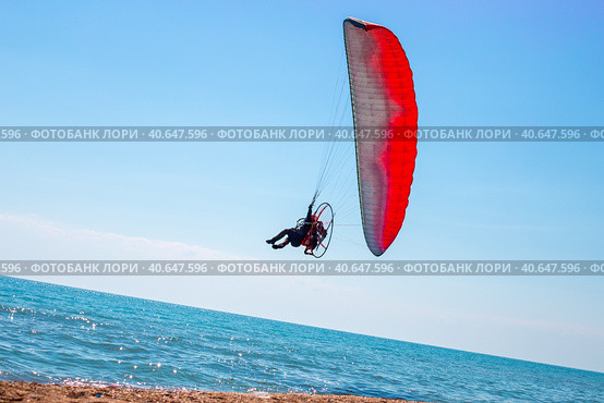 A man on a motor paraglider in the blue sky over the sea, the slope of the horizon. Sports and passion for flying. Стоковое фото, фотограф Коханова Наталья / Фотобанк Лори