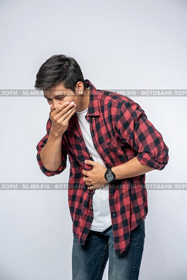 A man standing with a stomachache Put your hands on your stomach and cover your mouth. Стоковое фото, агентство Ingram Publishing / Фотобанк Лори
