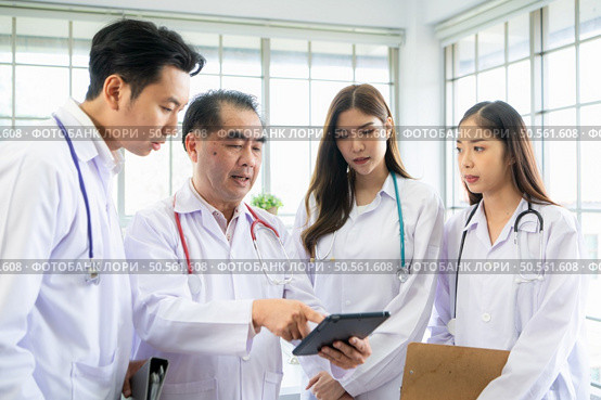 A medical professor and medical student discuss a case study involving disease therapy for a hospital patient. Стоковое фото, агентство Ingram Publishing / Фотобанк Лори