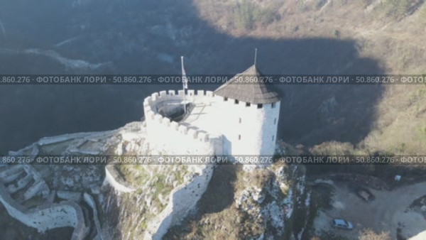 A mesmerizing drone flight around a petite medieval castle majestically perched on a mountain summit. This cinematic aerial showcase reveals the fortress's ancient stonework and commanding views. Стоковое видео, видеограф Виктор Ветошкин / Фотобанк Лори