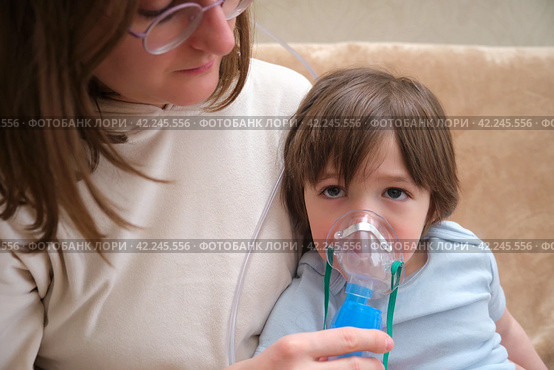 A mother woman with an inhaler helps her child cope with the disease. Inhalation for a sick asthmatic child to treat allergies. Стоковое фото, фотограф Андрей Журавлев / Фотобанк Лори