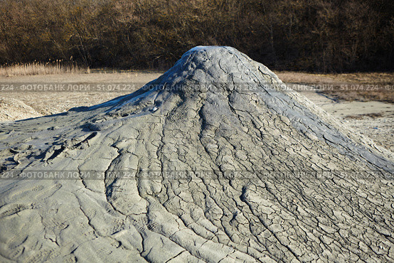 A mud volcano and a stream of grey clay from an eruption and gas escape. Cracked soil surface. Texture of a mudflow. Стоковое фото, фотограф Наталия Кирсанова / Фотобанк Лори