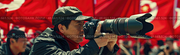 A person focuses intently on capturing photographs at a lively outdoor event marked by numerous red flags and enthusiastic participants. Стоковое AI-изображение, AI-художник Данила Большаков / Фотобанк Лори