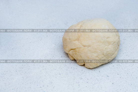 A piece of yeast dough is lying on the kitchen table waiting to be cooked. Кусок дрожжевого теста лежит на кухонном столе в ожидании приготовления. Стоковое фото, фотограф Дмитрий Березнев / Фотобанк Лори