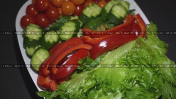 A plate of vegetables including tomatoes, cucumbers, and lettuce. Стоковое видео, видеограф Скрипачев Антон / Фотобанк Лори