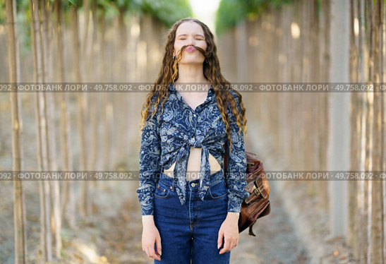 A playful and vibrant young woman poses confidently on a beautiful scenic pathway, showcasing her unique and trendy fashion sense while exuding her joyful and freespirited personality. A Joyful Young Woman Embracing Nature with Her Unique Fashion Style and Playful Attitude. Стоковое фото, агентство Ingram Publishing / Фотобанк Лори