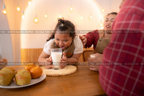 A plus-size family with a father wearing a prosthetic leg, Eat together after cooking and daughter drinks milk for health in the dining room of the house. Стоковое фото, агентство Ingram Publishing / Фотобанк Лори