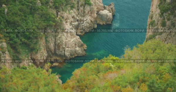 A rocky cove with clear blue water seen from above during a summer trip in Capri. Стоковое видео, видеограф Igor Tichonow / Фотобанк Лори