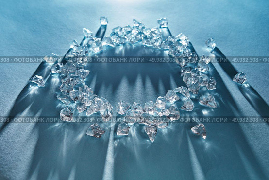 A round frame with ice cubes sparkling from the rays of light, long shadows on a blue background. Copy space for text. Concept of a cold drink. Shiny ice cubes in the form of a round frame on a blue background. Стоковое фото, агентство Ingram Publishing / Фотобанк Лори