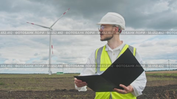 A safety inspector checks the wind turbine for any potential hazards on a rainy day prior to a thunderstorm. Стоковое видео, видеограф Strunov David / Фотобанк Лори