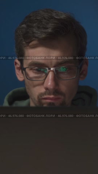 A serious male programmer wearing glasses, with green code reflecting on his lenses. Стоковое видео, видеограф Arsenii Palivoda / Фотобанк Лори