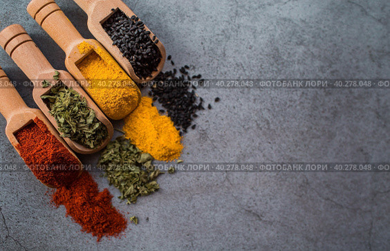 A set of fragrant spices. Turmeric, paprika, herbs and pepper in wooden spoons on a gray background. Free space for text. Стоковое фото, фотограф Photojuli / Фотобанк Лори