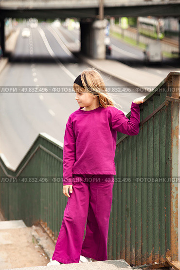 A Seven-Year-Old Girl Stands Gracefully on a Staircase Leading to a Bustling Street. Стоковое фото, фотограф Aleksandr Golubev / Фотобанк Лори
