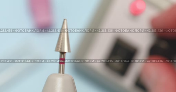 A specialist checks the balancing of a new carbide cutter for hardware manicure with a red notch, increases and decreases the rotation speed of the cutter. Стоковое видео, видеограф Сергей Чайко / Фотобанк Лори