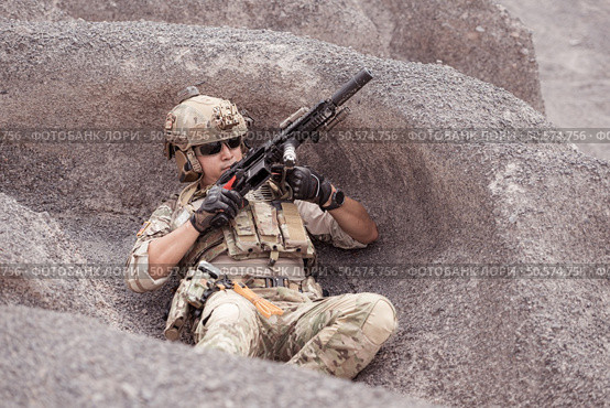 A Taliban soldier stands with a machine gun, Surrender to the allied soldiers, In the desert mountain terrain battlefield. Стоковое фото, агентство Ingram Publishing / Фотобанк Лори