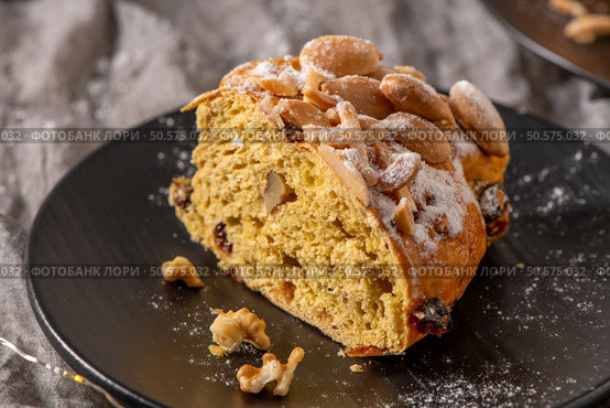 A tempting close-up of a Bolo Rainha slice, showcasing its almond topping and fruit-studded interior. This Portuguese Christmas cake is dusted with powdered sugar. Стоковое фото, агентство Ingram Publishing / Фотобанк Лори
