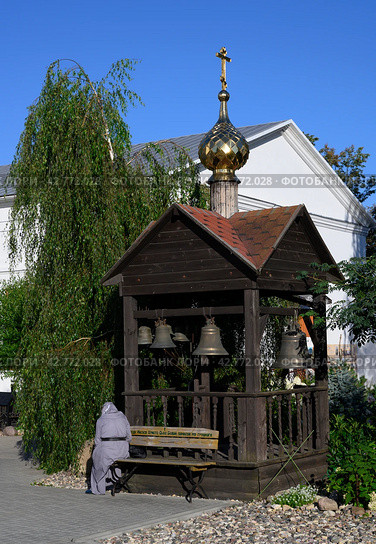 A thoughtful pilgrim on a bench near a gazebo with bells, dome and cross. The inscription on the bench: 'Lord Jesus Christ, Son of God, have mercy on me a sinner' Стоковое фото, фотограф Сергей Фролов / Фотобанк Лори