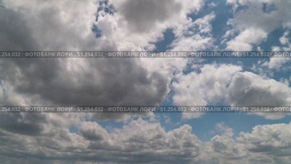 A time-lapse shot of a bright blue sky covered with large fluffy white cumulus clouds casting soft shadows in the bright daylight. Стоковое видео, видеограф Олег Альбертович Потаскуев / Фотобанк Лори