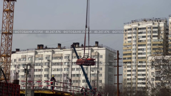 A tower crane lowers materials to the construction site. Construction of a shopping complex in a residential area. Стоковое видео, видеограф Ярославский Максим / Фотобанк Лори