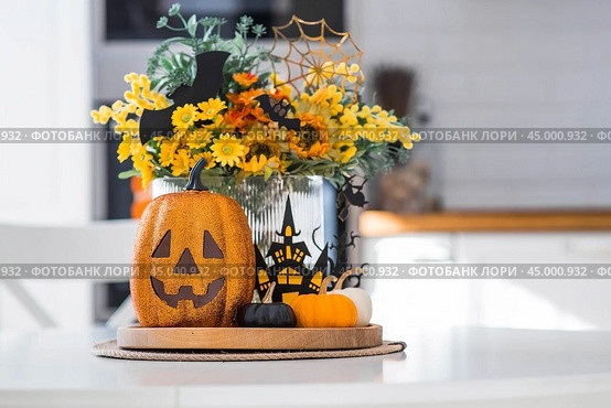 A vase of flowers, pumpkins and a scary castle with a witch on the background of a Scandi-style white kitchen interior. The concept of home and comfort. Autumn decor for Halloween. Стоковое фото, фотограф Photojuli / Фотобанк Лори