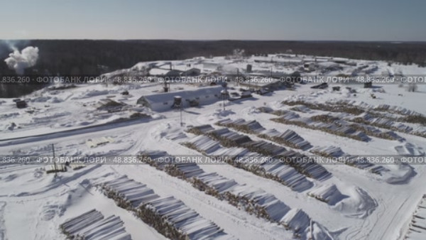 a view from a flying drone over a log warehouse at a woodworking factory in winter. Стоковое видео, видеограф Алексей Сергеев / Фотобанк Лори