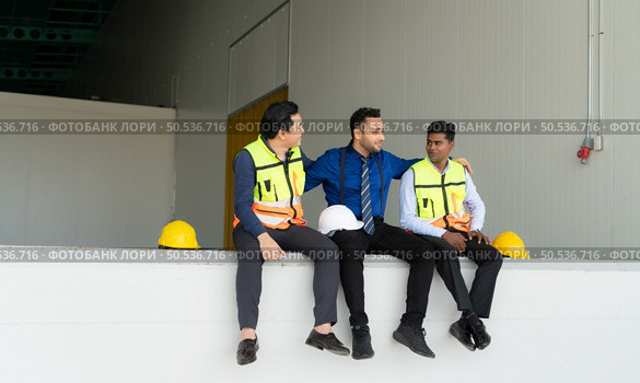 A warehouse manager and two employees are resting after dealing with how to organize the shelves in a large warehouse. Стоковое фото, агентство Ingram Publishing / Фотобанк Лори