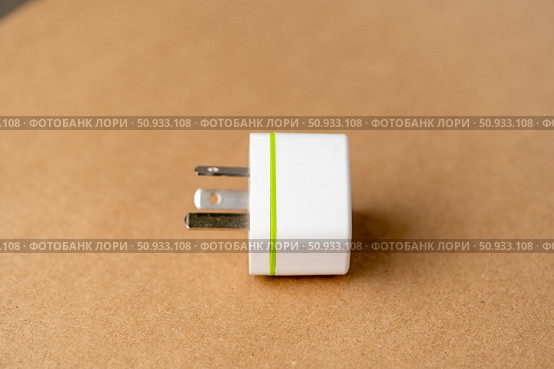 A white charger with a green stripe sits on a brown surface. Стоковое фото, фотограф Скрипачев Антон / Фотобанк Лори