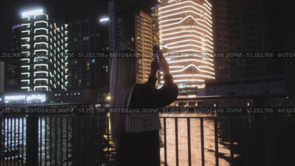 A woman captures urban beauty at night, showcasing stunning scenes. Стоковое видео, видеограф Cantemir Dumitru / Фотобанк Лори