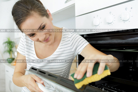a woman cleaning household oven. Стоковое фото, агентство Ingram Publishing / Фотобанк Лори