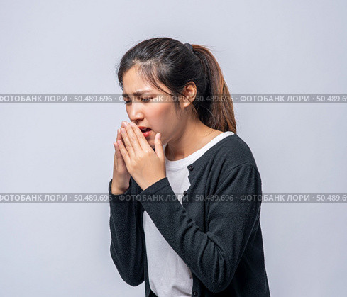 A woman coughing and covering her mouth with her hand. Стоковое фото, агентство Ingram Publishing / Фотобанк Лори