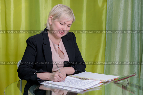 A woman director working in the office sits at the table, signs documents. Стоковое фото, фотограф Юрий Поздников / Фотобанк Лори