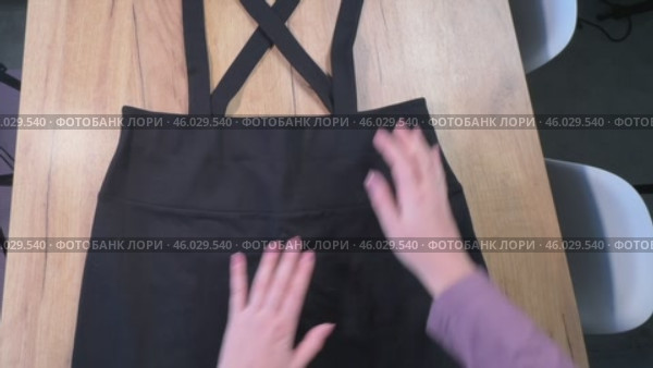 A woman is reviewing a sundress skirt. She is laying it out on the table. Photo from above. Стоковое видео, видеограф Vadzim Yakubovich / Фотобанк Лори