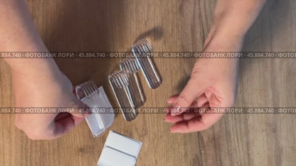 A woman is reviewing plastic hooks for the bathroom. She demonstrates the hooks and double-sided tape for installation. Vertical video. Стоковое видео, видеограф Vadzim Yakubovich / Фотобанк Лори