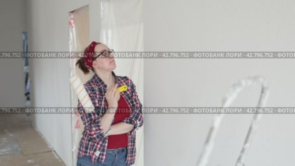A woman with a roller hands carefully examines a wall getting ready to paint. Стоковое видео, видеограф Ольга Коваленко / Фотобанк Лори