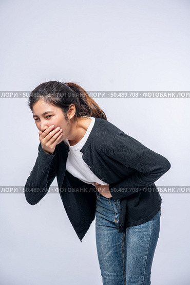 A woman with a stomachache puts her hands on her stomach and covers her mouth. Стоковое фото, агентство Ingram Publishing / Фотобанк Лори