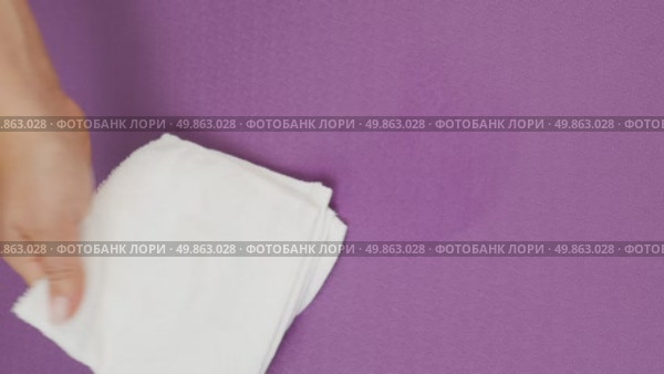 A woman's hand wipes water drops from a burgundy rug with a white cloth. Стоковое видео, видеограф Катерина Белякина / Фотобанк Лори