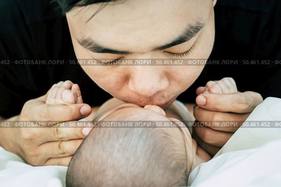 A young Asian father is sniffing his newborn baby. Стоковое фото, агентство Ingram Publishing / Фотобанк Лори