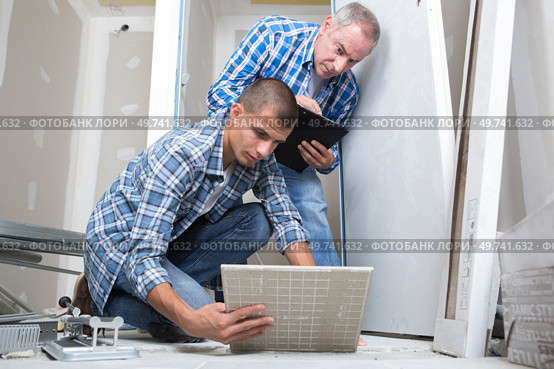 a young builder laying tiles. Стоковое фото, агентство Ingram Publishing / Фотобанк Лори