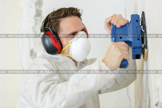 a young builder sanding wall. Стоковое фото, агентство Ingram Publishing / Фотобанк Лори