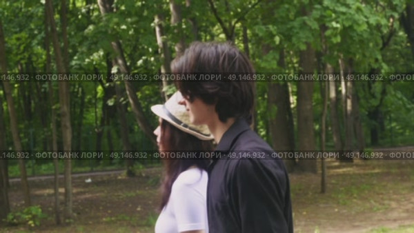 A young couple walks through a green summer park. Стоковое видео, видеограф Ярославский Максим / Фотобанк Лори