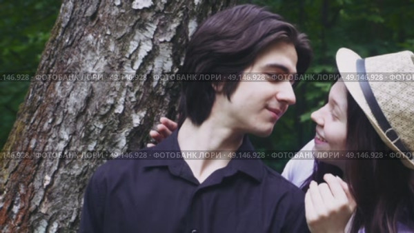 A young guy is waiting for his beloved girl by a tree in the forest. She closes his eyes from behind and they kiss. Стоковое видео, видеограф Ярославский Максим / Фотобанк Лори