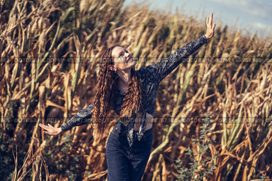 A young woman expresses her sheer joy while surrounded by a beautiful cornfield, dancing playfully and carefree amidst the tall golden stalks under a stunningly clear blue sky filled with sunshine. Joyful Dance in a Golden Cornfield, celebrating the beauty of nature and carefree moments. Стоковое фото, агентство Ingram Publishing / Фотобанк Лори