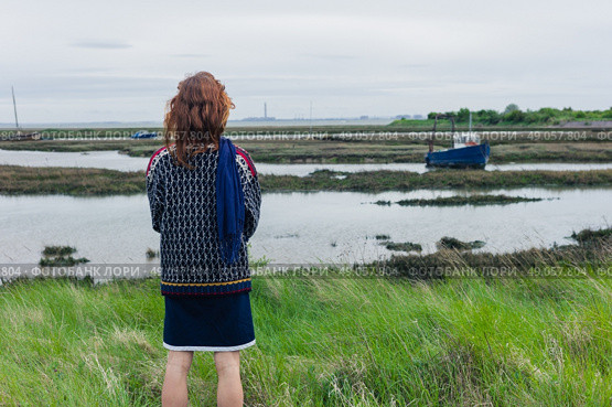 A young woman is walking in the marshes and is looking at a boat. Стоковое фото, агентство Ingram Publishing / Фотобанк Лори